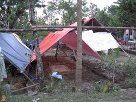 Tenda darurat dari terpal didirikan di kebun di dekat rumah yang terkena gempa dan menggunakan ti...