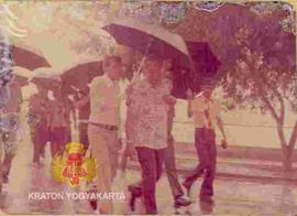 Sri Sultan Hamengku Buwono IX (berbaju batik) berjalan kehujanan dalam rangka menghadiri pembukaa...
