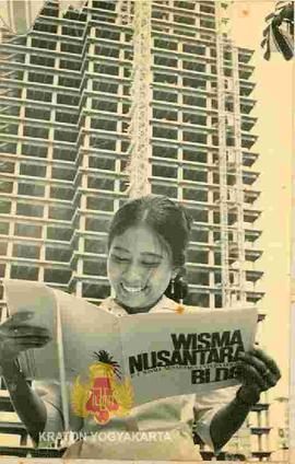 Seorang wanita sedang mengamati buku yang berkaitan dengan Gedung Wisma Nusantara.