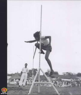 Seorang atlit wanita sedang melompati galah pada lomba lompat tinggi.