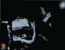 Dua orang pegawai sedang bekerja menggunakan mesin cetak.