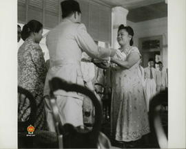 Tampak Presiden Soekarno sedang memberikan kenang-kenangan kepada seorang wanita wakil dari Anggo...
