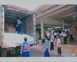 Pekerja sedang menurunkan kardus berisi bantuan untuk korban Gempa Jogja dari atas truk box.