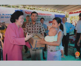 Sambil menggendong anak seorang ibu menerima bantuan berisi makanan dari perwakilan Yayasan Pondo...