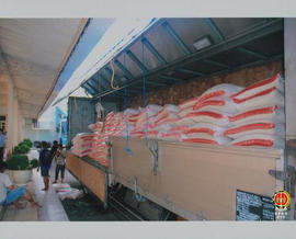 Para pekerja sedang menurunkan beras dari truk bok bantuan dari Perusahaan Rokok Sukun.