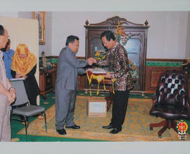 Pimpinan rombongan Komisi V DPR RI dan Sri Sultan HB X berjabat tangan sambil memegang nampan ber...