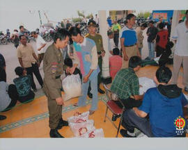 Seorang anggota linmas sedang memberikan sekantong beras yang diterima seorang korban gempa bumi.