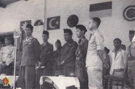 Panglima Besar Jenderal Soedirman beserta tamu undangan sedang berdiri pada acara pertemuan parta...
