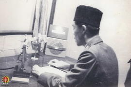 Panglima Besar Jenderal Soedirman sedang mencoba alat Radio Telepon, disaksikan tamu undangan yan...