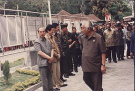 Presiden Soeharto berjalan di tengah-tengah para pejabat yang menyambut kunjungannya ke barak pen...